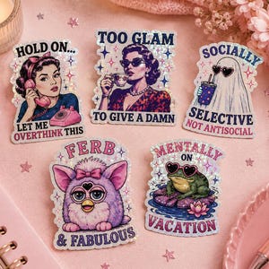 Könnte beinhalten: Fünf glitzernde Aufkleber mit Retro-Illustrationen und Text. Die Aufkleber zeigen eine Frau am Telefon, eine Frau mit einer Teetasse, ein Geist mit Sonnenbrille, ein Furby und ein Frosch. Der Text enthält "Hold On...", "Too Glam", "Socially Selective", "Ferb & Fabulous" und "Mentally on Vacation."