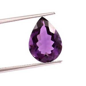 May include: A pear-shaped amethyst gemstone with a deep purple hue. The gemstone is held in place by a pair of tweezers.