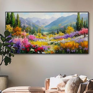 Può includere: Un dipinto di paesaggio rettangolare con cornice nera. L'opera raffigura un vivace campo di fiori colorati nelle tonalità del rosso, giallo, viola e arancione, che conduce a una catena montuosa sullo sfondo. Il dipinto è appeso sopra un divano in pelle marrone.
