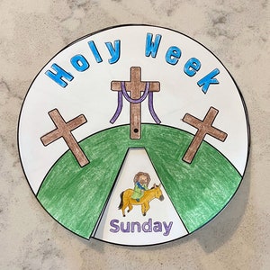 May include: A colorful paper plate with the words "Holy Week" written in blue letters. The plate is divided into sections, each with a different image related to the events of Holy Week. The center section shows a green hill with three brown crosses and a purple rope. The bottom section shows a green hill with a yellow donkey and a man riding it. The text "Sunday" is written below the donkey.