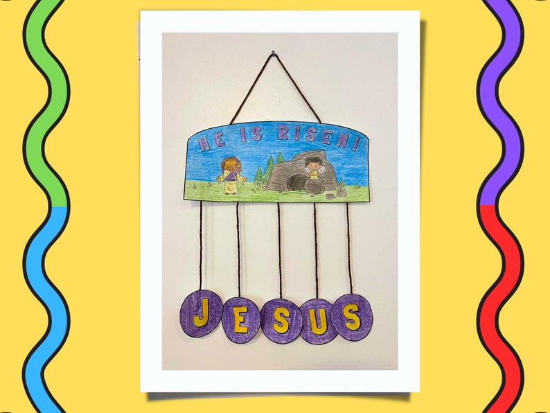 Puede incluir: Una manualidad de papel morado y azul con las palabras "He is Risen!" y un dibujo de una persona saliendo de una cueva. La manualidad tiene cinco c&iacute;rculos morados colgando de ella con la palabra "JESUS" escrita en letras amarillas.