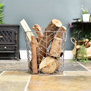 May include: A silver metal log basket with a chevron pattern, filled with stacked firewood logs.