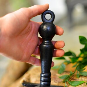 K&ouml;nnte beinhalten: Ein schwarzer Flaschenverschluss mit strukturierter Oberfl&auml;che. Der Verschluss hat einen Ring oben, einen kugelf&ouml;rmigen Mittelteil und einen langen, zylindrischen Sockel. Das Design ist schlicht und elegant, passend f&uuml;r Weinflaschen.