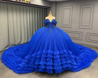 May include: A royal blue ball gown with a sweetheart neckline and a full skirt with multiple layers of ruffles. The gown features intricate beading and lace detailing on the bodice and sleeves.