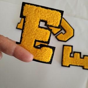 May include: Yellow felt letter E with black outline. The letter is thick and has a fuzzy texture.