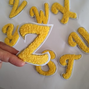 May include: Yellow felt letters of the alphabet, including the letters V, W, X, Y, Z, A, G, and T. The letters are outlined in white and have a fuzzy texture.