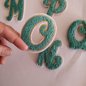 May include: Set of five green felt letters with gold trim. The letters are M, O, P, K, and C. The letters are in a cursive font.
