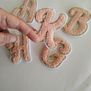 May include: Four pink fuzzy letters with gold trim, spelling out the word "A B C"