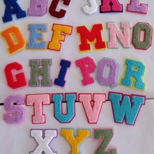 May include: A set of 26 colourful felt letters, each letter is individually cut out and has a white outline. The letters are arranged in alphabetical order, starting with A and ending with Z.