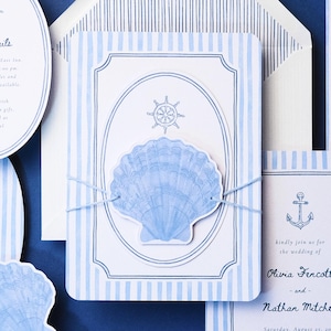 May include: Nautical-themed wedding invitation suite with blue and white striped patterns. The invitation features a seashell and a ship's wheel design. Additional cards include details and an anchor. The text reads "Olivia Fercott and Nathan Mitchell".