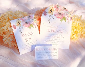 May include: A set of three baby shower cards with a floral design. The cards are white with pink and yellow flowers. The text on the cards reads "Baby in Bloom", "Thank You", and "Books for Baby".