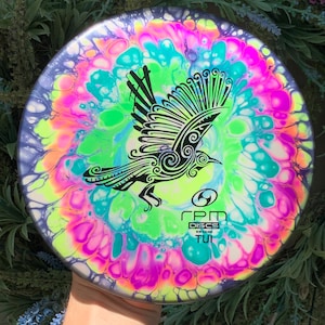 May include: A brightly coloured disc with a black and white bird design. The disc has a swirl pattern of pink, green, blue and yellow. The text "RPM Discs New Zealand TUI" is printed on the disc.