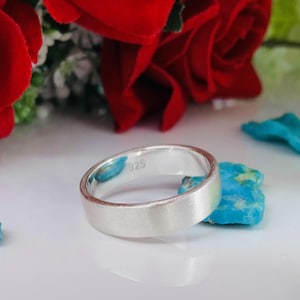May include: A silver band ring with a brushed finish. The ring is marked with "925" on the inside.