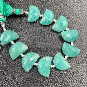 Puede incluir: Un hilo de piedras preciosas de amazonita. Las piedras, de color turquesa claro, est&aacute;n talladas en forma de media luna y ensartadas con peque&ntilde;as cuentas blancas. Una borla verde est&aacute; unida al extremo del hilo.