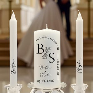 May include: A set of three white wax candles in clear glass holders. The center pillar candle features the text "TWO SHALL BECOME ONE", the initials "B S", the names "Beatrice + Stephen", and the date "03. 17. 2026". The two taper candles are personalized with the names "Beatrice" and "Stephen".
