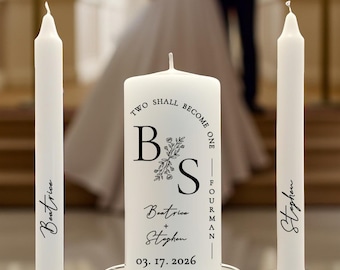 May include: A set of three white wax candles in clear glass holders. The center pillar candle features the text "TWO SHALL BECOME ONE", the initials "B S", the names "Beatrice + Stephen", and the date "03. 17. 2026". The two taper candles are personalized with the names "Beatrice" and "Stephen".