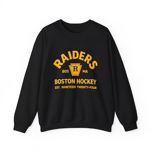 May include: Black crew neck sweatshirt with a yellow Raiders logo and the text "BOSTON HOCKEY EST. NINETEEN TWENTY-FOUR". The logo features a yellow "R" inside a shield.