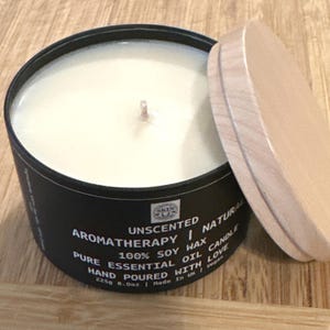 May include: A black candle jar with a wooden lid. The candle is unscented and made with 100% soy wax. The label reads "Unscented Aromatherapy Natural Pure Essential Oil Candle 100% Soy Wax Hand Poured With Love 225g 8.0oz | Made in UK | Vegan".