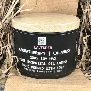 May include: A black candle jar with a wooden lid. The label reads "LAVENDER AROMATHERAPY | CALMNESS 100% SOY WAX PURE ESSENTIAL OIL CANDLE HAND POURED WITH LOVE 225g 8.0oz | Made In UK | Vegan".