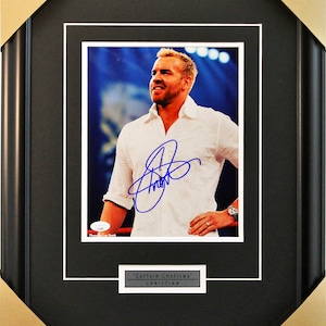 May include: A framed photograph of a man in a white shirt with a blue signature. The text "Captain Charisma" and "Christian" is below the photo.