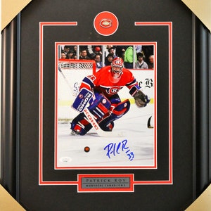 May include: A framed photograph of Patrick Roy, a former professional ice hockey goaltender, wearing a Montreal Canadiens jersey. The photo is signed by Roy and includes the team logo.