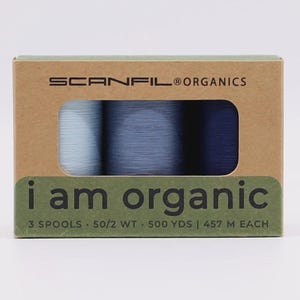 May include: A rectangular cardboard box containing three spools of thread in shades of light blue, medium blue, and dark blue. The box is labeled SCANFIL ORGANICS and i am organic, with text indicating 3 spools, 50/2 WT, and 500 YDS or 457 M each.