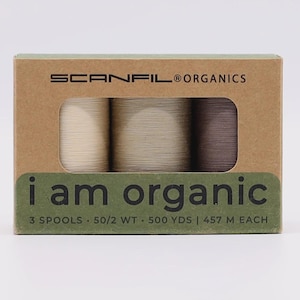 May include: A rectangular cardboard box containing three spools of thread in cream, beige, and brown. The box is labeled SCANFIL ORGANICS and i am organic, with text indicating 3 spools, 50/2 WT, and 500 YDS or 457 M of thread on each spool.