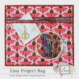 May include: A quilted project bag with a floral pattern in red and white, featuring a zipper closure. Inside, there's a white fabric with a fish design, gold scissors, embroidery floss, and a wooden hoop. The text "Easy Project Bag" is at the bottom.