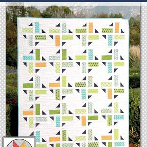 May include: A handmade quilt with a geometric pattern. The quilt features a white background with colorful blocks in shades of green, orange, and blue. The word "Division" is at the top. The quilt is displayed outdoors.