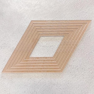 May include: A tan-colored quilting template with a diamond shape and a central square cutout. The template has multiple nested diamond outlines, with text indicating sizes from 2.5 to 4.5 inches. The text "Laundry Basket Quilts" is also visible.