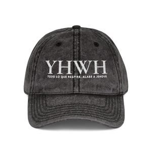 Puede incluir: Una gorra de béisbol gris carbón con efecto lavado al ácido que presenta un bordado blanco con el texto YHWH y debajo, TODO LO QUE RESPIRE, ALABE A JEHOVÁ. La gorra tiene una visera curva, un panel frontal estructurado y un botón superior.