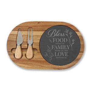 Puede incluir: Tabla de queso ovalada de madera con una inserción de pizarra. Incluye un cuchillo y un tenedor para queso con mangos de madera. La inserción de pizarra tiene las palabras "Bless the Food before us, the Family beside us, and Love between us."