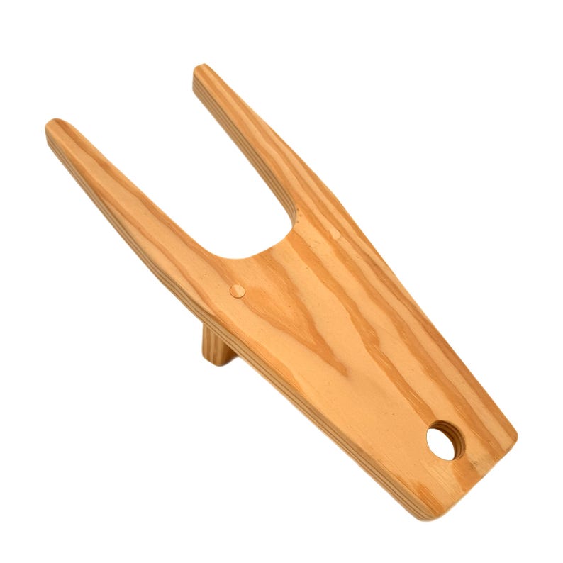 May include: A wooden boot jack with a natural wood finish. The jack has two prongs and a hole in the base.