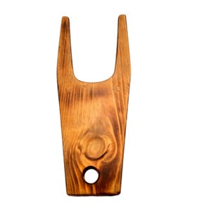 May include: A wooden boot jack with a brown finish. The jack has two prongs and a hole in the center.