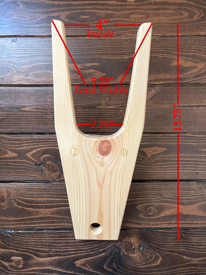 May include: Wooden V-shaped stand with a 4-inch inside width, 5.25-inch total width, and 13.75-inch height. The stand is made of light wood and has a hole in the bottom.