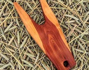 May include: A handcrafted wooden yarn swift, featuring a two-tone design with a rich reddish-brown center and lighter orange-brown edges. The swift has a distinctive Y-shape with a hole at the base, ideal for holding yarn skeins. The wood grain is visible.