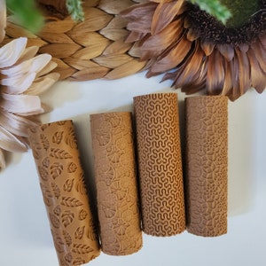 May include: Four brown rolling pins with different embossed patterns. The patterns include leaves, swirls, and geometric shapes.