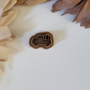 May include: A brown plastic cookie cutter shaped like a pickup truck carrying a pumpkin.
