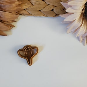 May include: A brown plastic cookie cutter shaped like a manta ray.