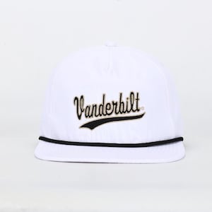 May include: White baseball cap with the word "Vanderbilt" embroidered in black script across the front. A black rope detail runs along the brim. The cap is a classic, casual accessory.