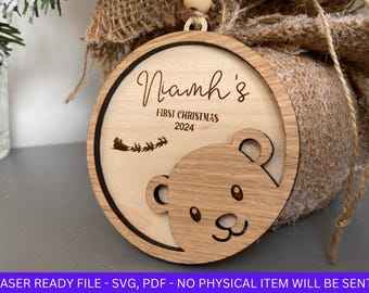 May include: A wooden Christmas ornament with the text "Niamh's First Christmas 2024" and a cartoon bear face.