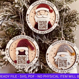 May include: Three wooden Christmas decorations featuring a Santa Claus, a gnome, and a girl wearing a red hat. Each decoration has a QR code and the text "Scan to Track Santa".