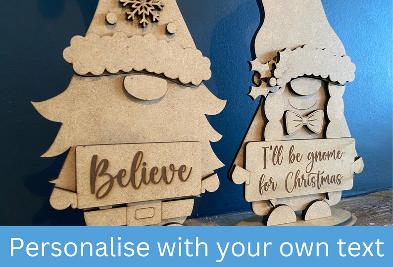 May include: Two wooden Christmas gnomes, one holding a sign that says "Believe" and the other holding a sign that says "I'll be gnome for Christmas".