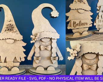 May include: Two wooden gnome figures, one with a beard and a snowflake on its hat, the other with long hair and a bow tie. Both gnomes are holding signs, one says "Believe" and the other says "I'll be gnome for Christmas".