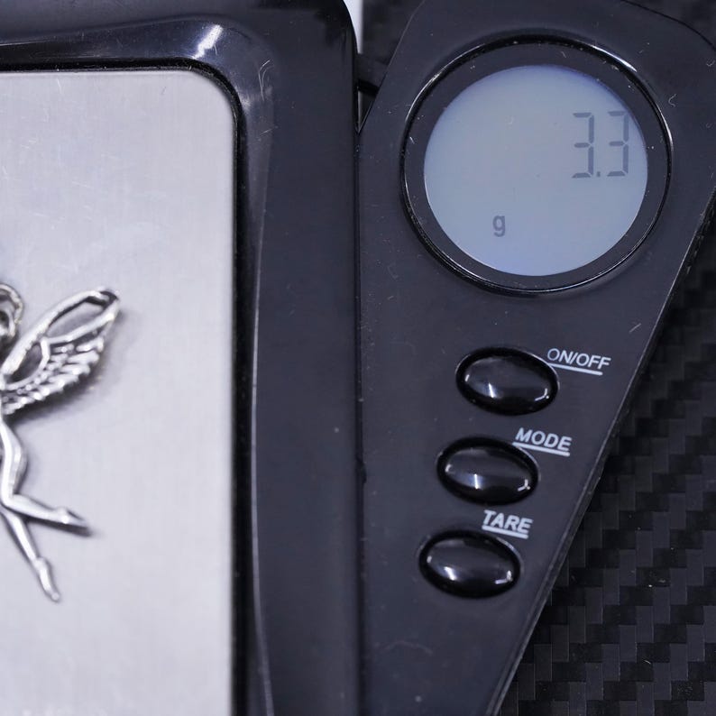 K&ouml;nnte beinhalten: Eine schwarze digitale Waage mit einer silbernen Wiegeplattform. Die Waage zeigt "3,3 g" auf dem Bildschirm an. Die Waage hat Tasten mit den Beschriftungen "ON/OFF", "MODE" und "TARE".