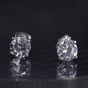 May include: A pair of silver stud earrings with clear round cubic zirconia stones.