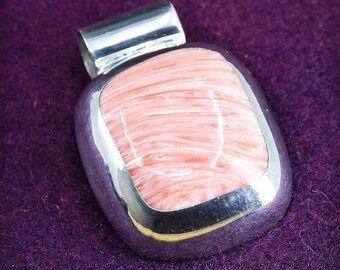 May include: A silver pendant with a pink and white striped stone set in a silver bezel.