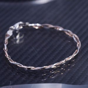 Puede incluir: Un brazalete trenzado de plata y oro rosa con cierre de broche.
