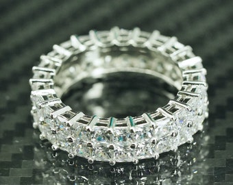 May include: A silver eternity band ring with a double row of square-cut cubic zirconia stones.