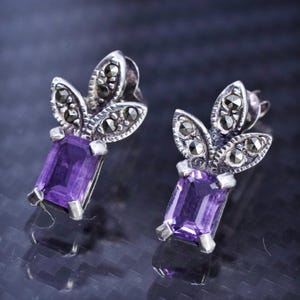 May include: A white ceramic mug with a black handle and the text "But First, Coffee" in a bold, black font. The mug is set against a neutral background, highlighting its simple design.